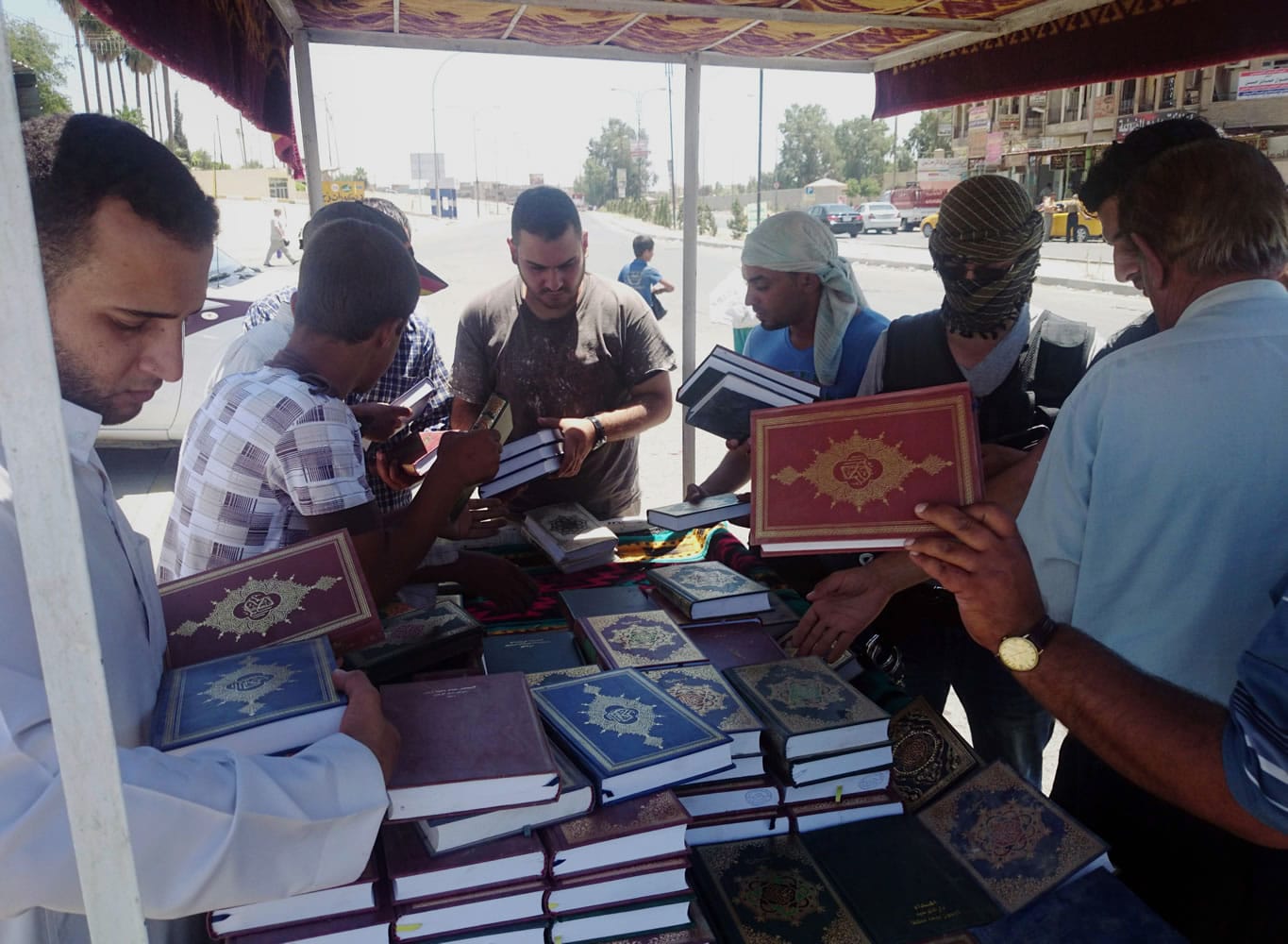 A fighter, third from right, with the al-Qaida-inspired Islamic State of Iraq and the Levant distributes copies of the Quran, Islamu2019s holy book, to local residents in central northern city of Mosul, Iraq.