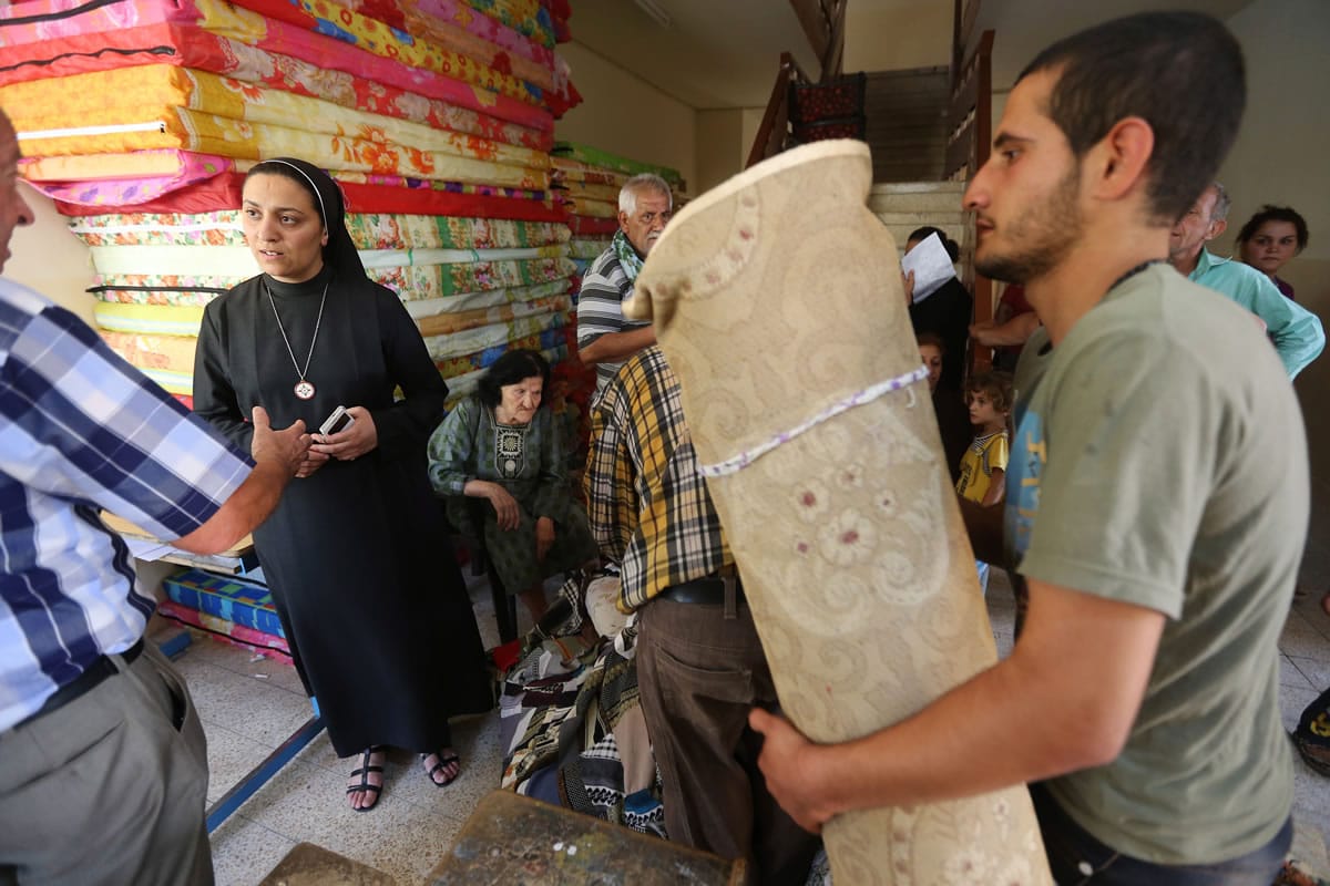 An Iraqi nun, center left, speaks today with a Christian man who fled with his family from the Christian villages near Mosul province in Iraq, at a school which serves as a shelter for the displaced Christian families, in Ainkawa, a suburb of Irbil, Iraq, which has a majority Christian population. The extremist Islamic State of Iraq and the Levant executed at least 160 captive soldiers earlier this month in the northern city of Tikrit, Human Rights Watch said today, citing an analysis of satellite imagery and grisly photos released by the militants.