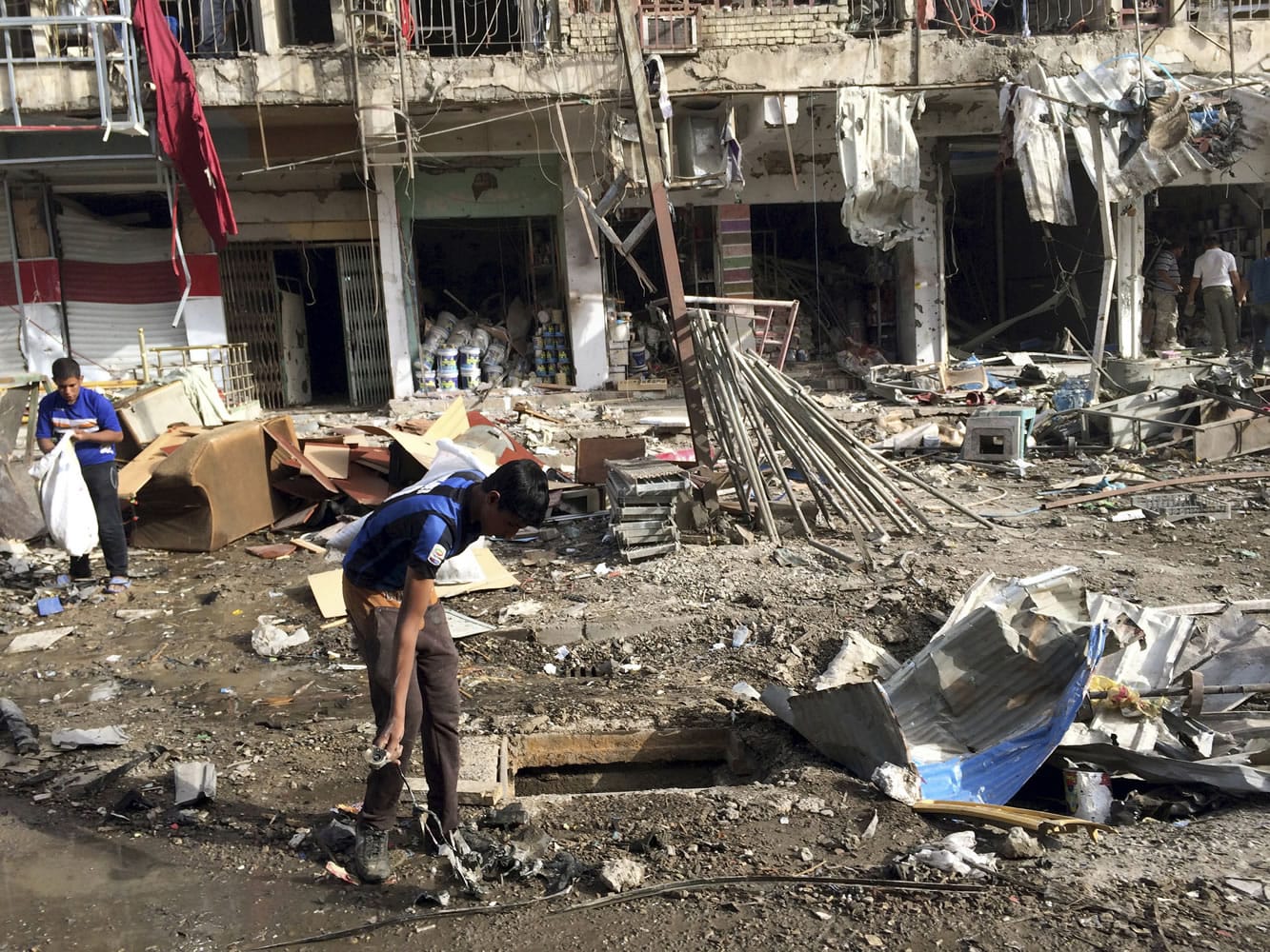 People clean up in the aftermath of a car bombing in the southeastern district of New Baghdad, Iraq, on Sunday.