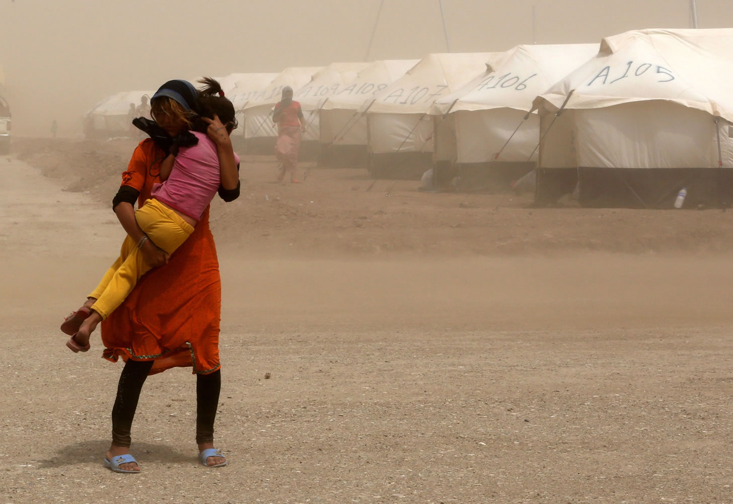 An internally displaced Iraqi woman holds her sister during a sandstorm at a new camp outside the Bajid Kandala camp in Feeshkhabour town, Iraq, Tuesday, Aug. 19, 2014. Some 1.5 million people have been displaced by fighting in Iraq since the Islamic State's rapid advance began in June, and thousands more have died. The scale of the humanitarian crisis prompted the U.N. to declare its highest level of emergency last week.