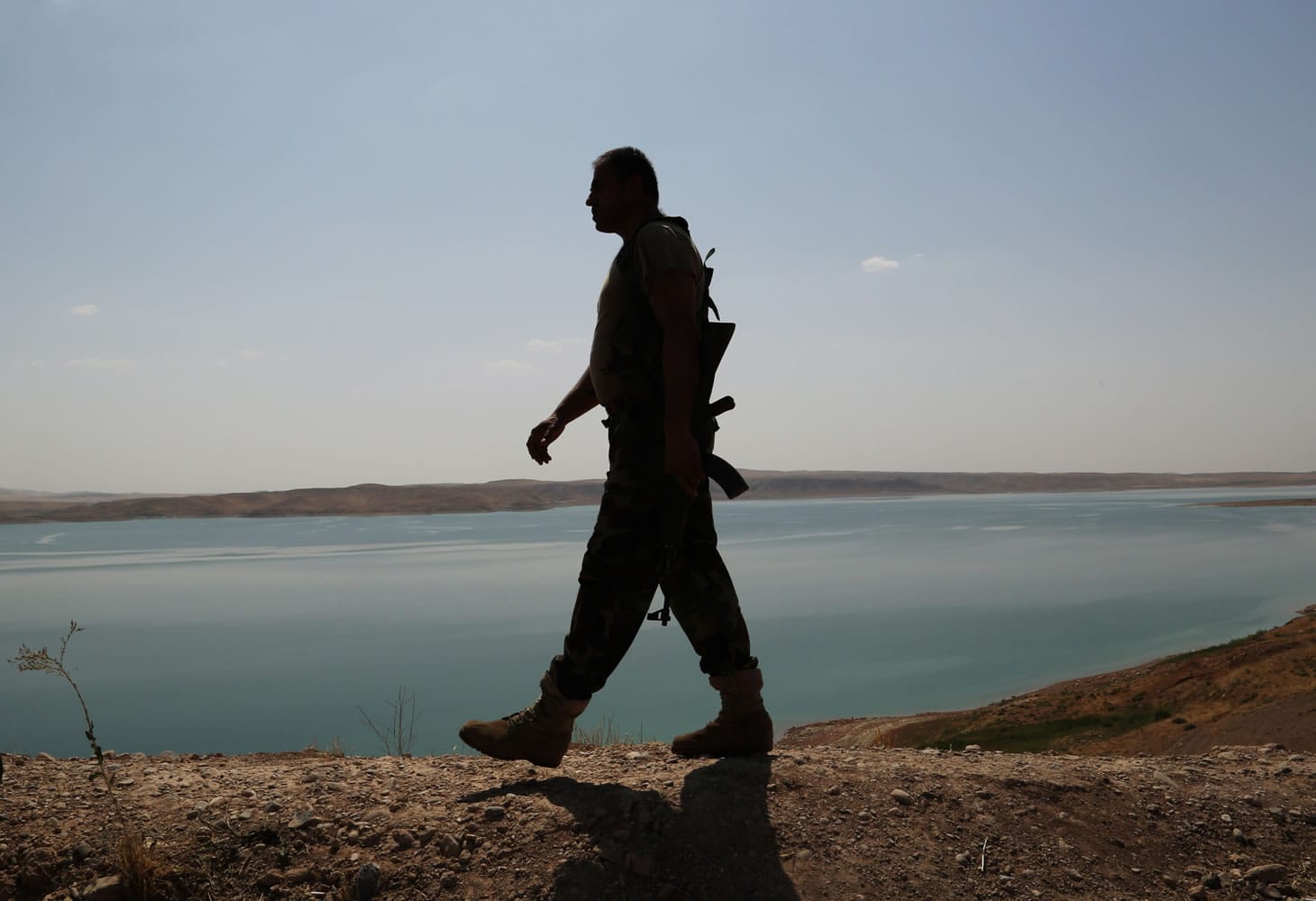A Kurdish peshmerga fighter patrols Sunday near the Mosul Dam at the town of Chamibarakat outside Mosul, Iraq. Kurdish forces took over parts of the largest dam in Iraq on Sunday, less than two weeks after it was captured by the Islamic State extremist group, Kurdish security officials said, with aid from U.S.