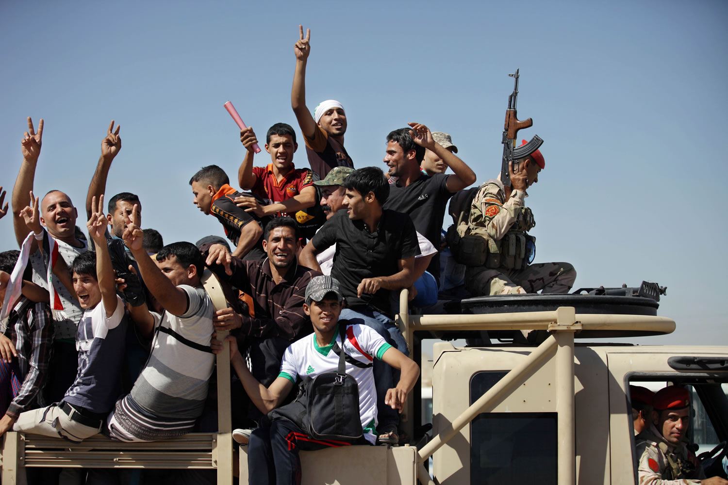 Iraqi men flash victory signs as they leave the main recruiting center to join the Iraqi army in Baghdad, Iraq, on Tuesday after authorities urged Iraqis to help battle insurgents.