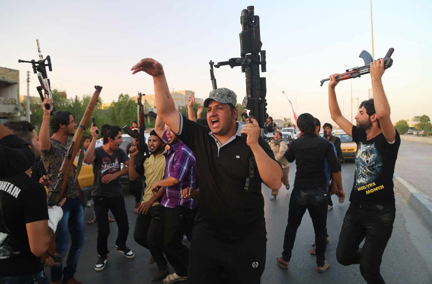 Shiite tribal fighters raise their weapons and chant slogans against the al-Qaida-inspired Islamic State of Iraq and the Levant (ISIL) in Basra, Iraq's second-largest city, 340 miles southeast of Baghdad, Iraq, Sunday, June 15, 2014.