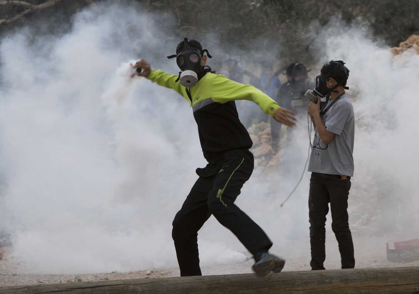 A Palestinian protester Friday throws back a tear gas canister fired by Israeli soldiers during clashes following a protest against the nearby Jewish settlement of Kdumim, in the West Bank village of Kufr Qaddum. A Palestinian was shot and arrested after officials say he threw acid at an Israeli family.