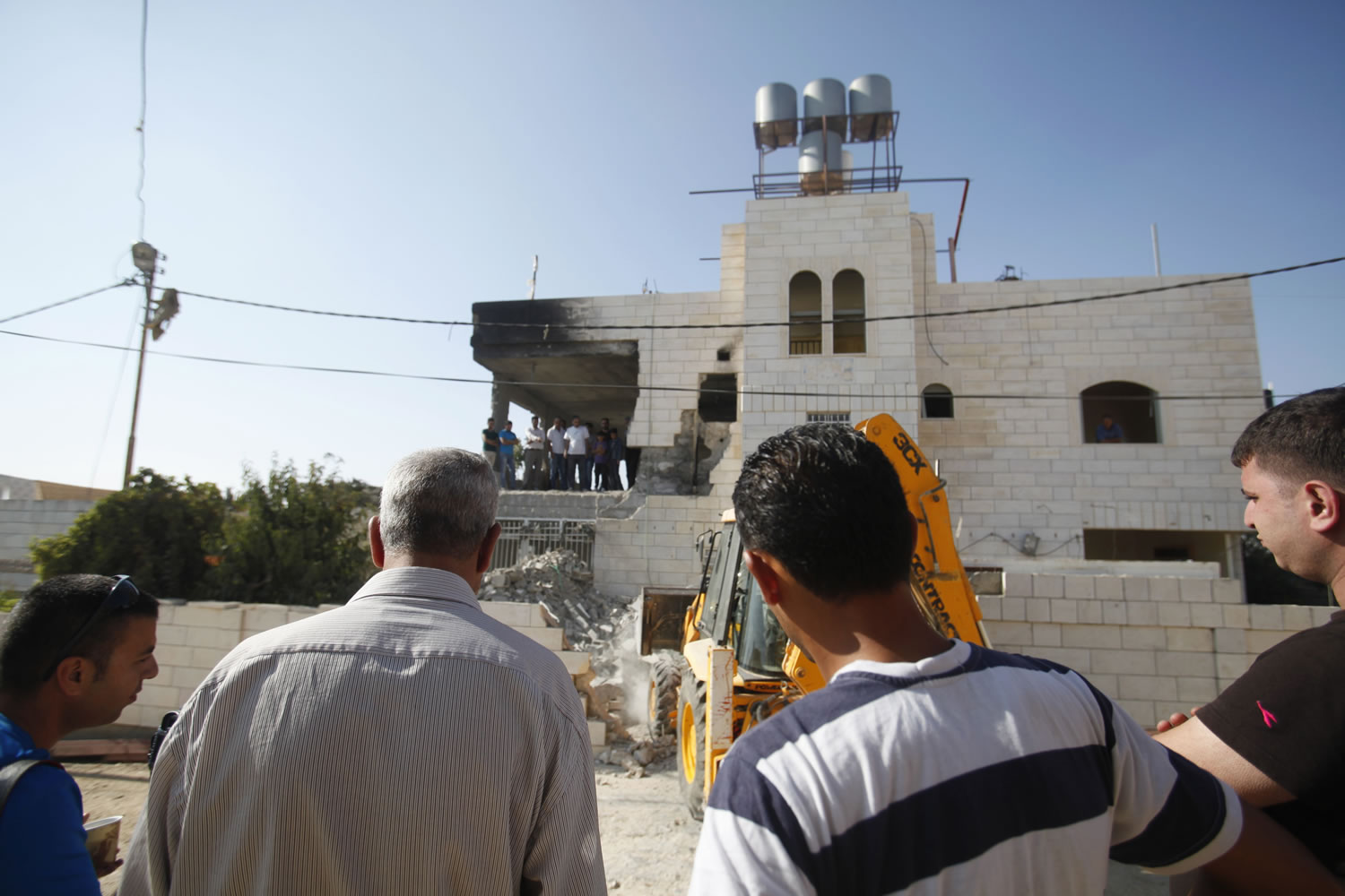 Palestinians look at the home of Amer Abu Aisheh, one of three Palestinians identified by Israel as suspects in the killing of three Israeli teenagers, after it was demolished by the Israeli army in the West Bank city of Hebron on Monday.