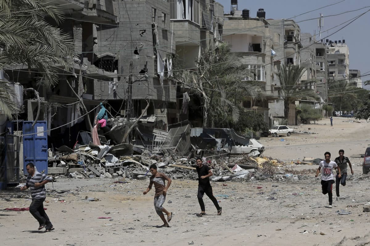 Palestinians run to take cover Sunday after an Israeli strike hits a three-story building belonging to the Abdul Hadi family in Gaza City in the northern Gaza Strip.
