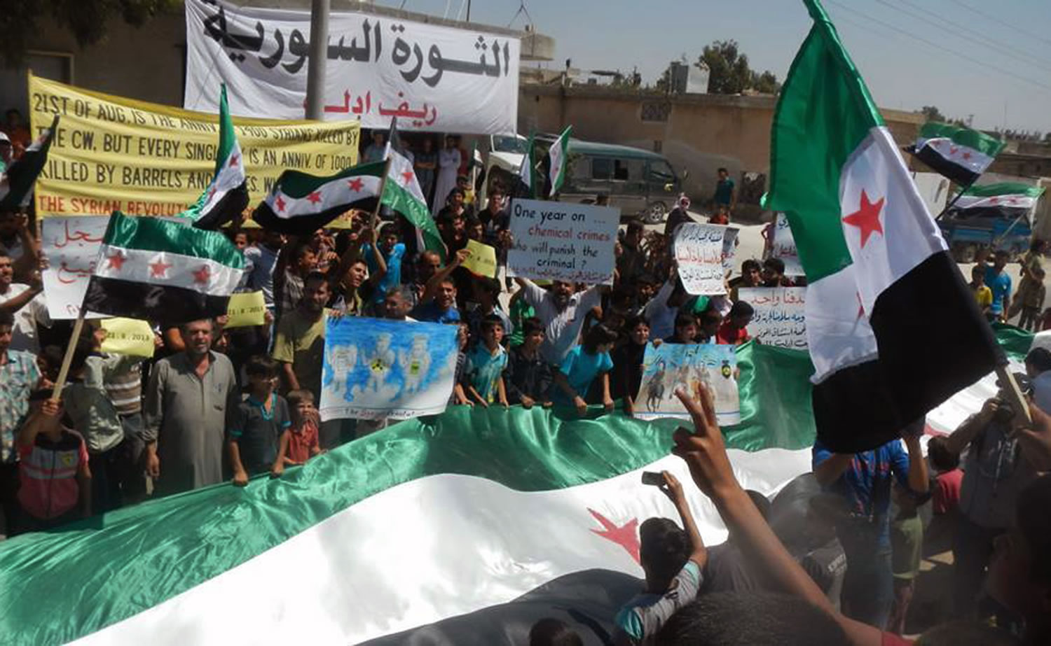 Anti-Syrian government protesters carry banners and a giant Syrian revolution flag during a demonstration in Idlib province, northern Syria on Friday.