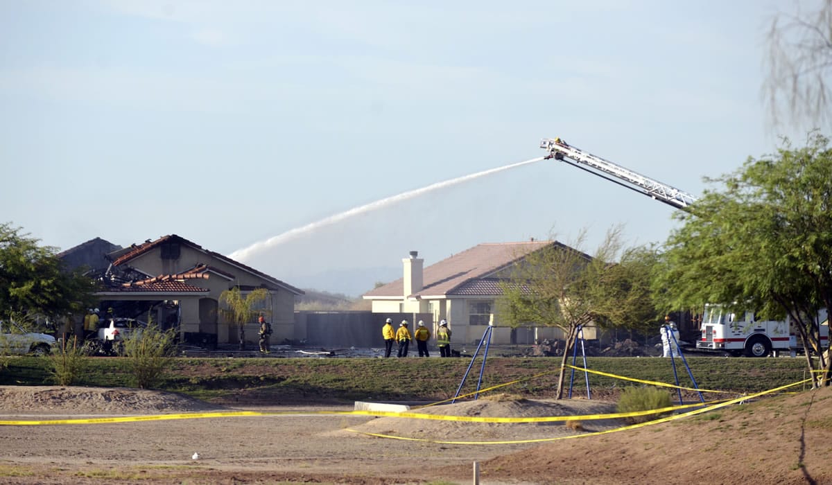 Water is sprayed onto buildings after a Marine jet crashed into a residential area in the desert community of Imperial, Calif., setting two homes on fire Wednesday.