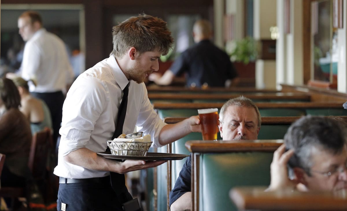 Waiter Spencer Meline serves a customer at Ivar's Acres of Clams restaurant on the Seattle waterfront Wednesday, May 14, 2014. While the Seattle mayor is proposing to raise the minimum wage to $15 in the coming years to the highest level in the nation, some activists say that's too slow and are threatening to take the issue to voters with a ballot measure that would force a raise sooner. As the mayor's plan is being debated by the council, businesses are sounding the alarm that raising the wage too quickly could hurt their revenue and force them to either hire fewer workers or let go more of their employees, while popular restaurateurs have emphatically argued for counting tips in total compensation.