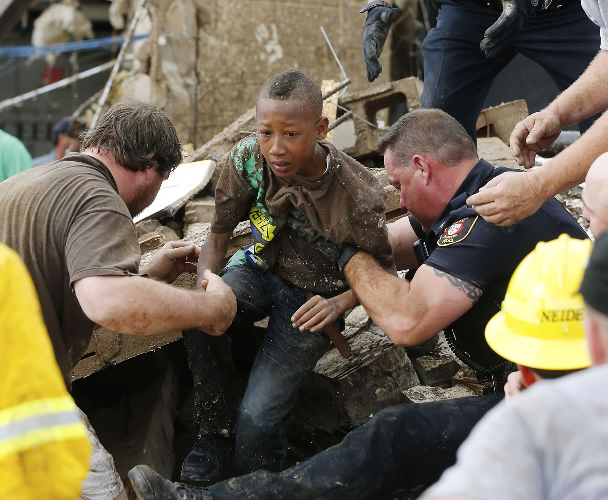 Cam'ron Richardson, center, is carried out of the rubble of Plaza Towers Elementary school after a massive tornado hit in Moore, Okla., on May 20, 2013.