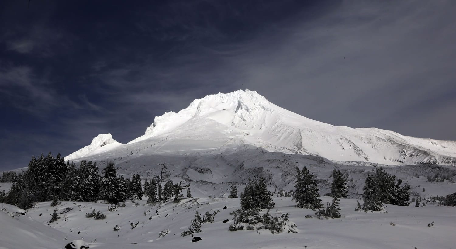 Clouds lift briefly and allow the sun to highlight Mount Hood wearing a fresh coat of snow in October near Government Camp, Ore.