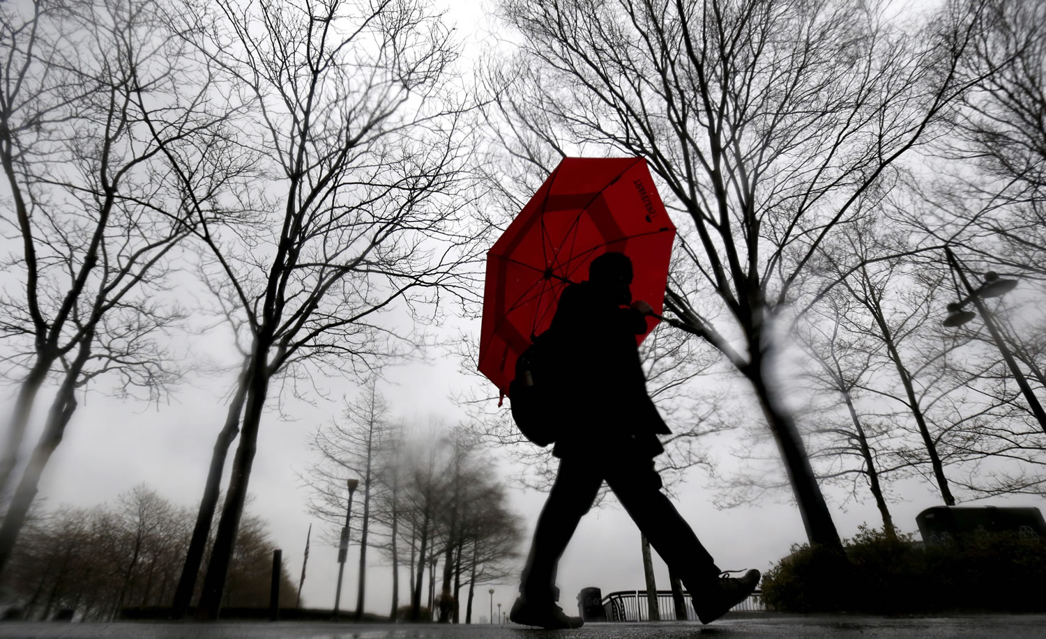 A man walks near the Hudson River waterfront in the rain Wednesday in Hoboken, N.J.
