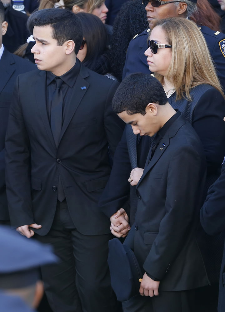 Jaden Ramos, bottom right, bows his head as the casket of his father, New York City police officer Rafael Ramos, is put into a hearse following funeral services Saturday at Christ Tabernacle Church in New York.