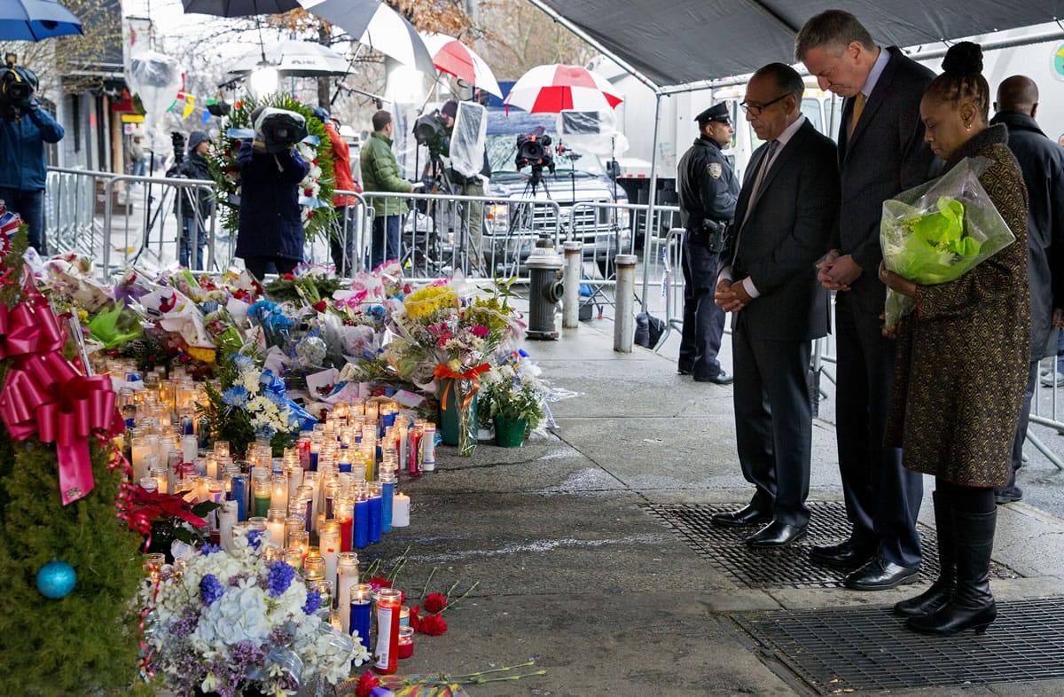 From left, Pastor Michael Durso, New York City Mayor Bill de Blasio and New York City first lady Chirlane McCray visit a makeshift memorial Tuesday near the site where New York Police Department officers Rafael Ramos and Wenjian Liu were shot and killed in the Brooklyn borough of New York.
