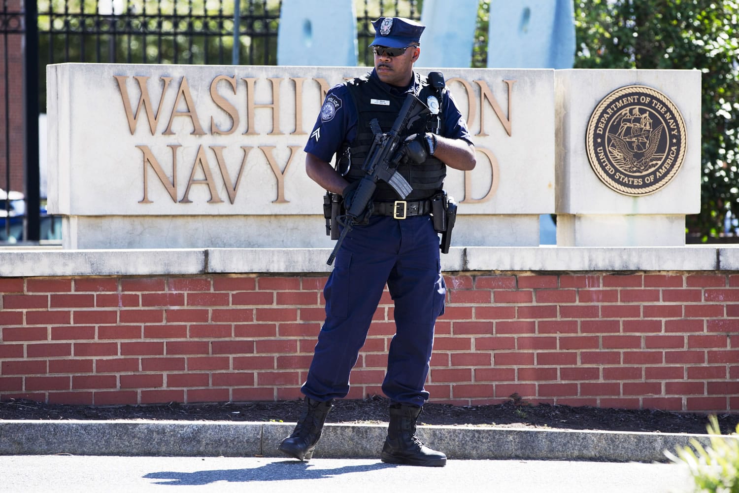 An armed officer who said he is with the Defense Department stands near guard the gate at the Washington Navy Yard the day after a gunman launched an attack inside the Yard in September 2013.