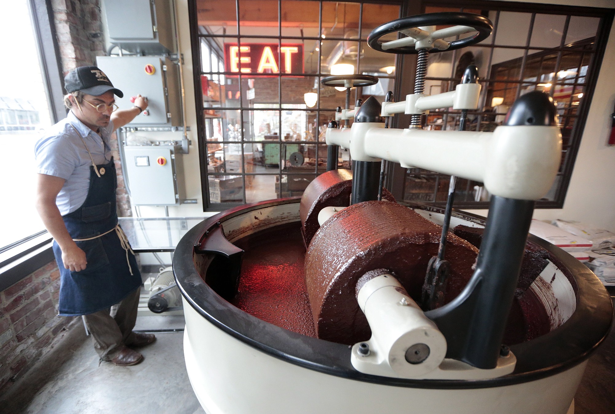 Scott Witherow, founder and owner of Olive and Sinclair Chocolate, operates his stone grinders to grind cacao beans April 6 in the East Nashville area of Nashville, Tenn.