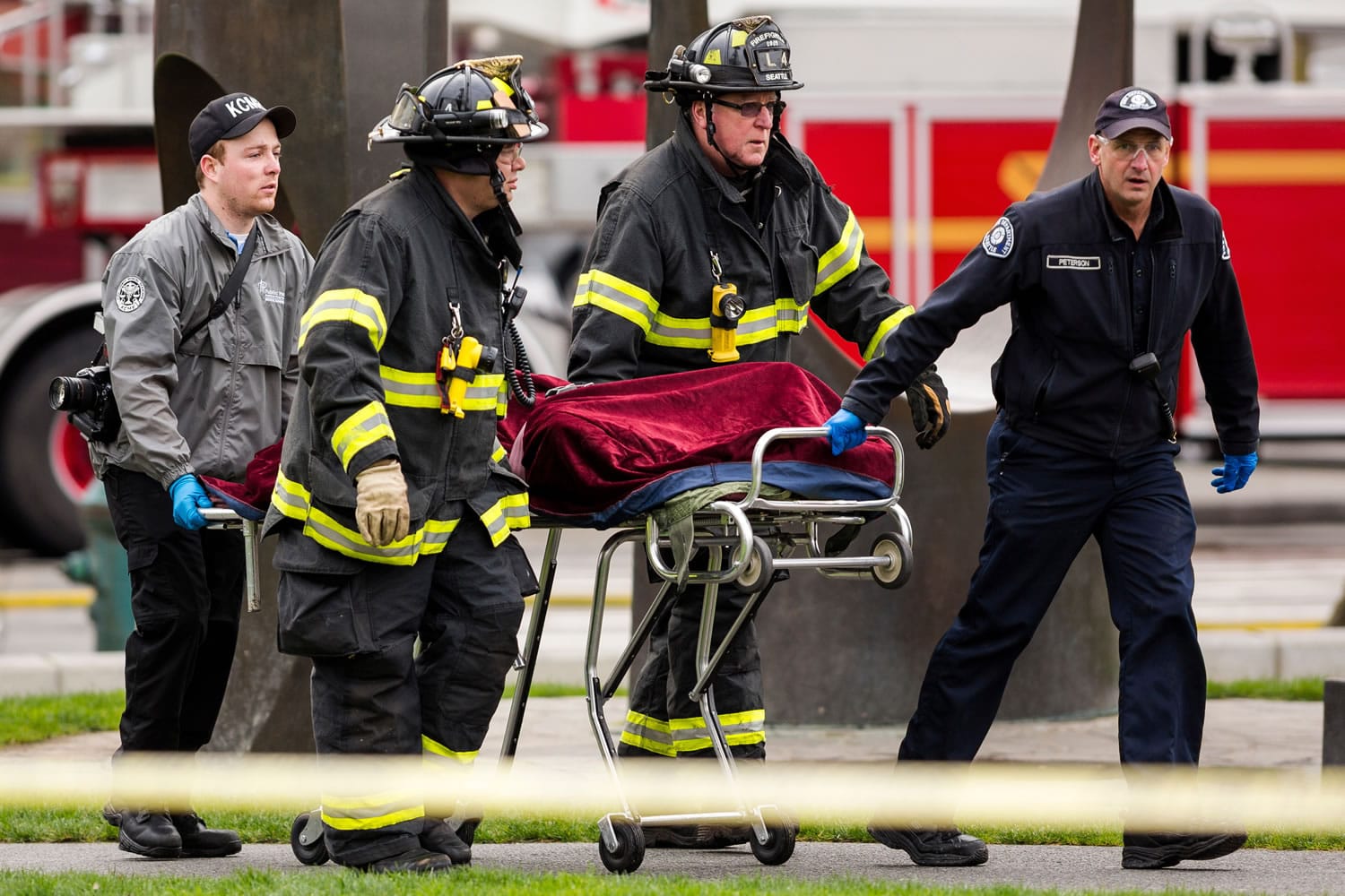 Emergency personnel wheel away one of two bodies from the aftermath of a news helicopter crash Tuesday in Seattle.
