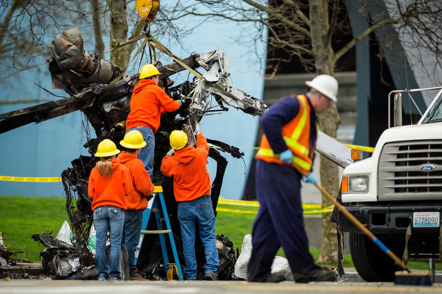 Crews move twisted and burned rotors from the scene where a news helicopter crashed into a street and burst into flames Tuesday near Seattle's Space Needle, killing two people on board, badly injuring a man in a car and sending plumes of black smoke over the city during the morning commute.
