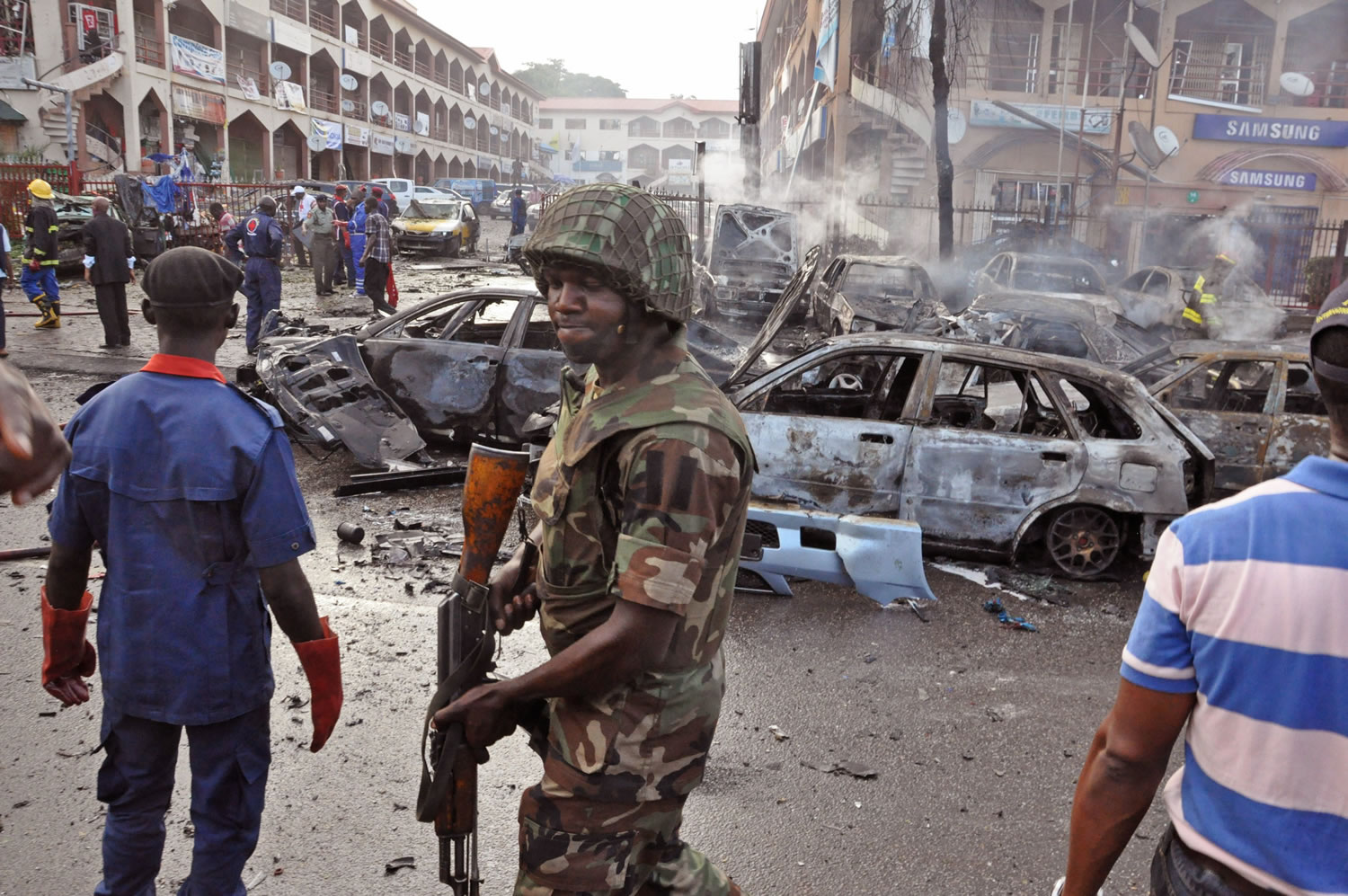 A Nigerian soldier walks past the scene of an explosion at a shopping mall Wednesday in Abuja, Nigeria.