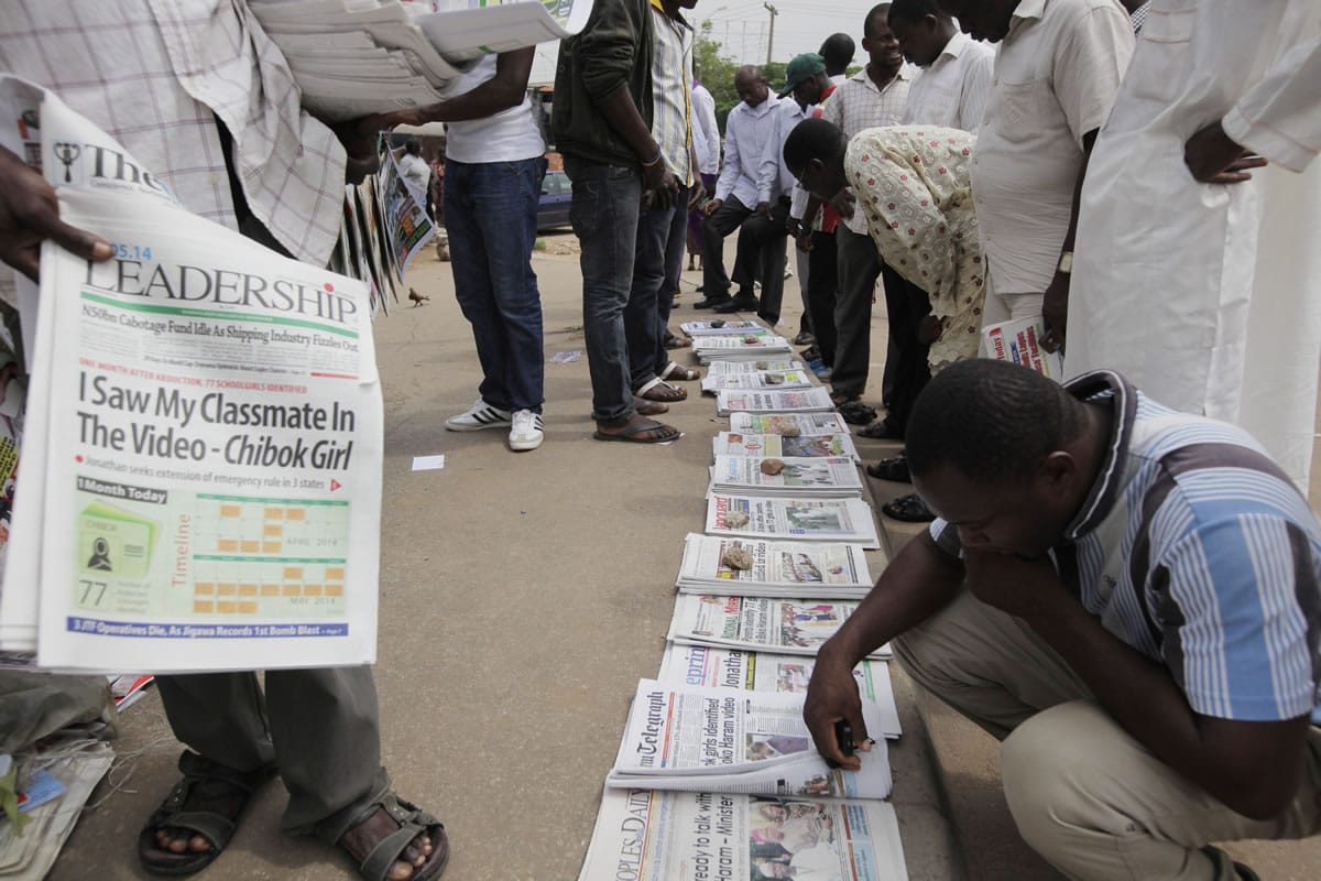 People read local newspapers on the street, with headlines stating 'I saw my classmate in the video' referring to the kidnapped school girls of a government secondary school Chibok, in a video released on Monday by Boko haram in Abuja, Nigeria, on Wednesday.
