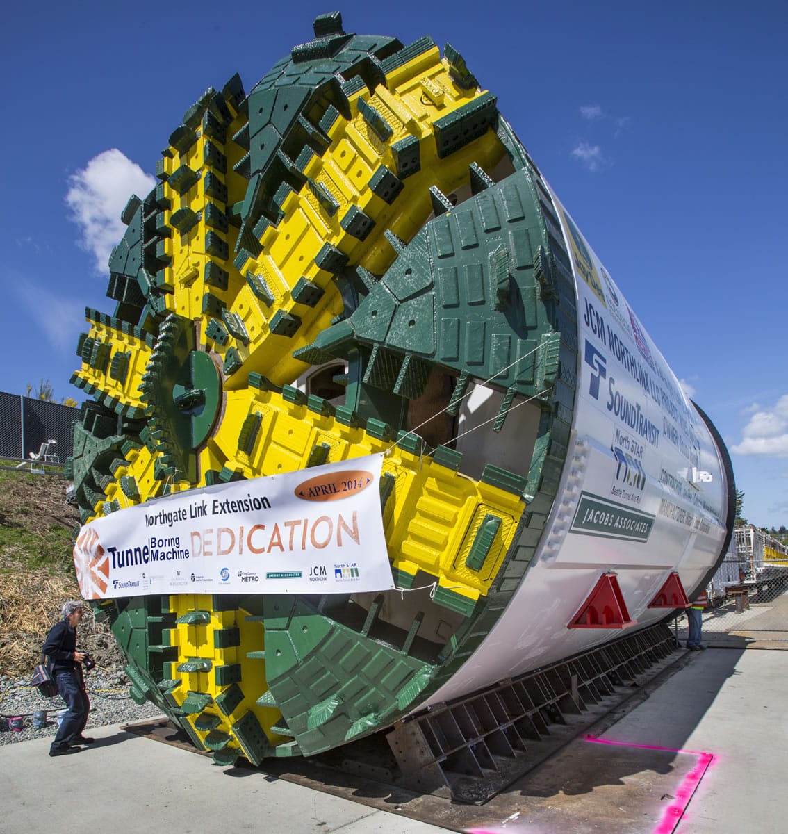 A news photographer is dwarfed by the Northgate Link light rail tunnel boring machine that was dedicated Monday afternoon and will be launched to drill the southbound tunnel from the Northgate portal to Husky Stadium this summer.