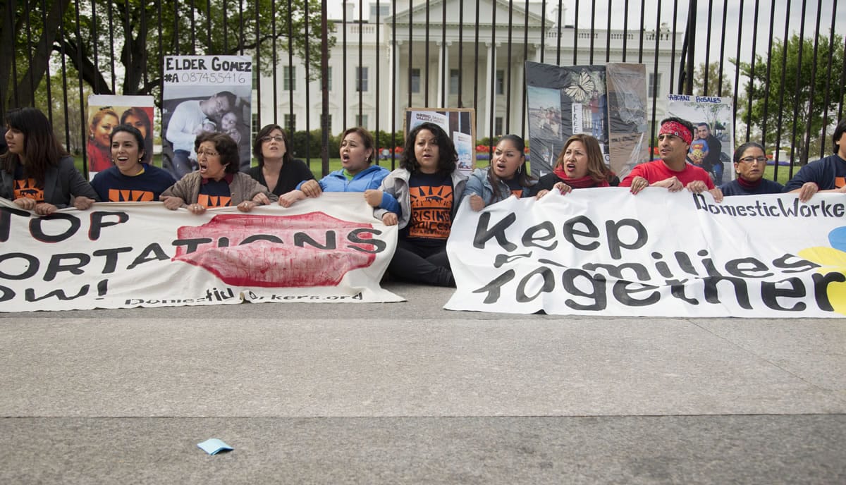 Demonstrators sit on the sidewalk outside the White House in Washington during an April demonstrations to demand President Barack Obama stop deportation of immigrants.