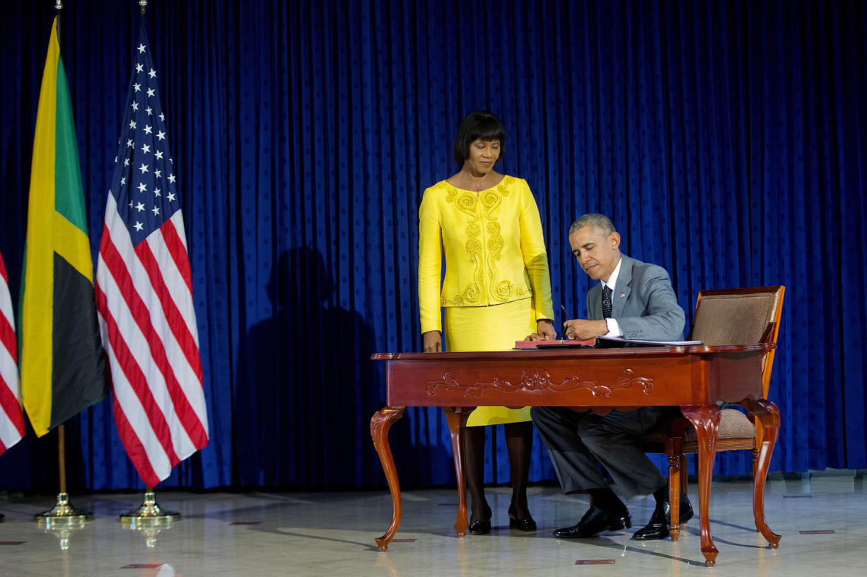 President Barack Obama, accompanied by Jamaican Prime Minister Portia Simpson-Miller, signs the guest book prior to their bilateral meeting at the Jamaica House on Thursday in Kingston, Jamaica.