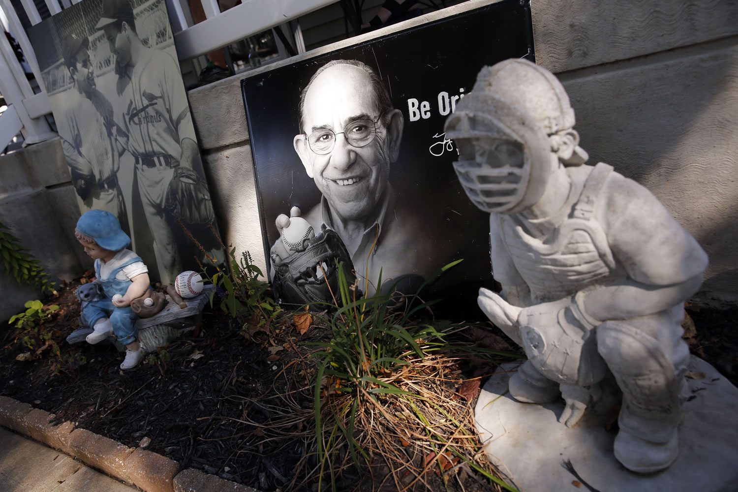 Photos and baseball-themed lawn ornaments sit outside the boyhood home of Yogi Berra Wednesday  in St. Louis. Berra, who grew up in St. Louis, played in more World Series games than any other major leaguer and was a three-time American League Most Valuable Player, died Tuesday of natural causes at his home in New Jersey, according to Dave Kaplan, the director of the Yogi Berra Museum. He was 90.