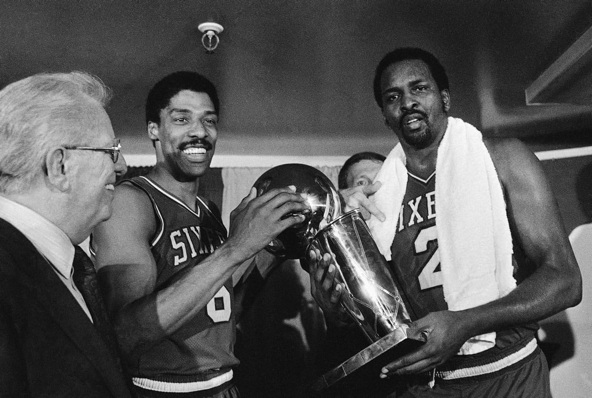 Philadelphia 76ers Julius Erving, left, and Moses Malone, right, hold the NBA Championship trophy May 31, 1983 after defeating the Los Angeles Lakers in  Los Angeles. Malone, a three-time NBA MVP and one of basketball's most ferocious rebounders, died Sunday according to a The Philadelphia 76ers statement. He was 60.