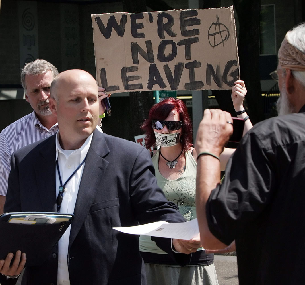 Register-Guard files
Chaun Benjamin, General Services Administration service centers director, left, hands out eviction notices July 10, 2012, as a protester holds a sign displaying the Occupy Eugene group's intent to stay in the Federal Building plaza in Eugene, Ore.