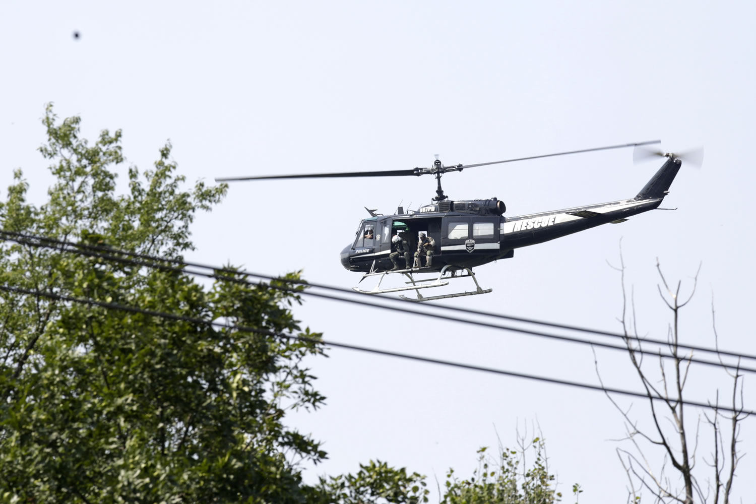 A police helicopter patrols a swampy area near route 59 and Rollins in Fox Lake, Ill., during a manhunt after an officer was shot and killed while pursuing a group of suspicious men, Tuesday.