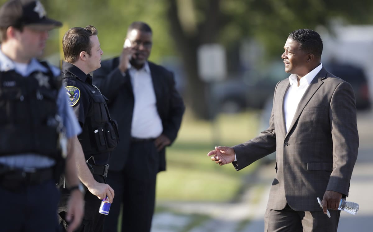 Harvey Mayor Eric J. Kellogg, right talks with police officers as law enforcement officials continue to negotiate with at least one hostage-taker for the release of two children and two adults he is still holding inside a house in the southern Chicago suburb of Harvey on Wednesday. The standoff began at 12:45 p.m. Tuesday when Harvey police responded to reports from a neighbor of a possible burglary at the home. Two officers were wounded in an initial exchange of gunfire.