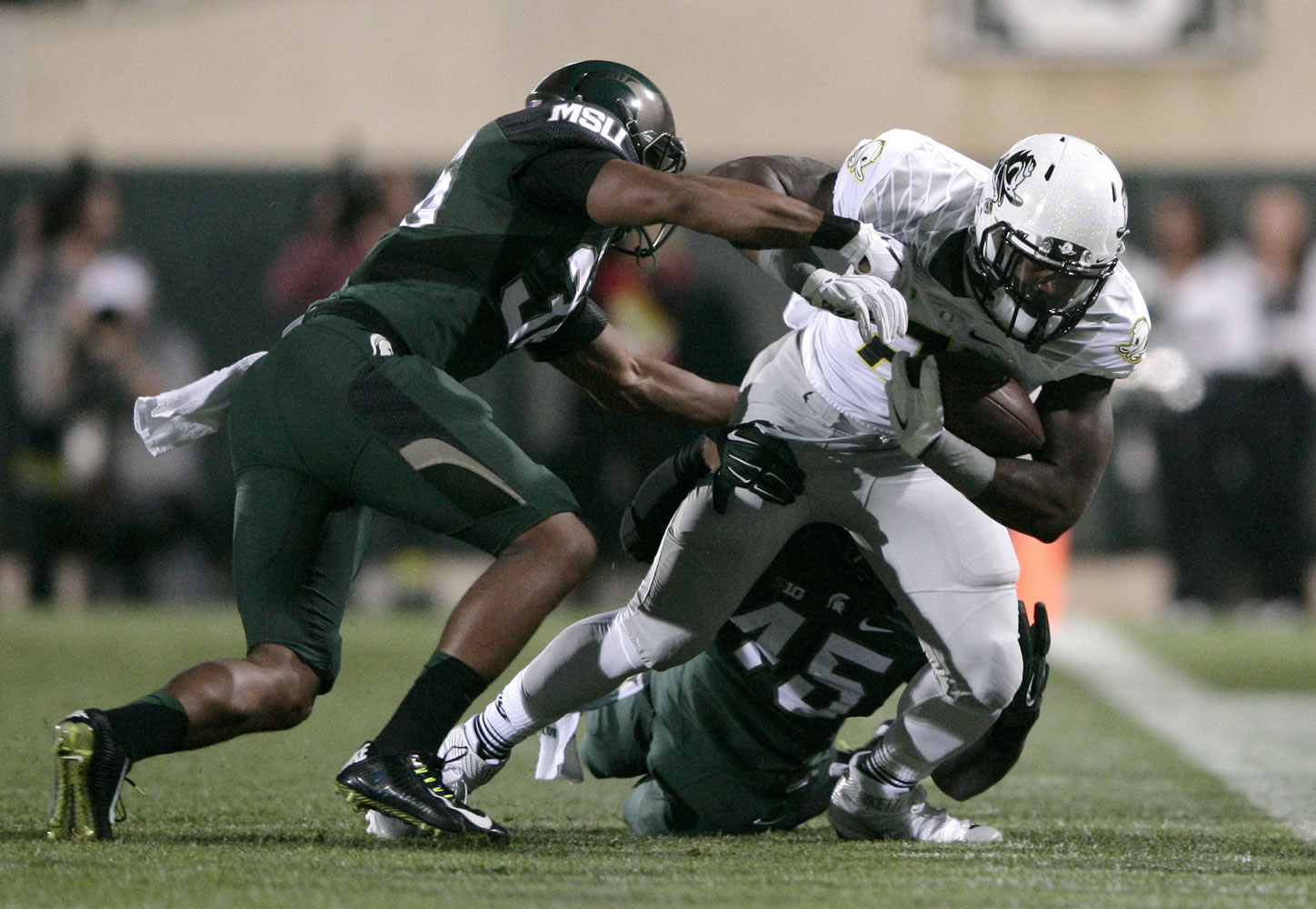 Oregon's Royce Freeman, right, is tackled by Michigan State's Darien Harris (45) and Arjen Colquhoun, left, during the first quarter of an NCAA college football game, Saturday, Sept. 12, 2015, in East Lansing, Mich.