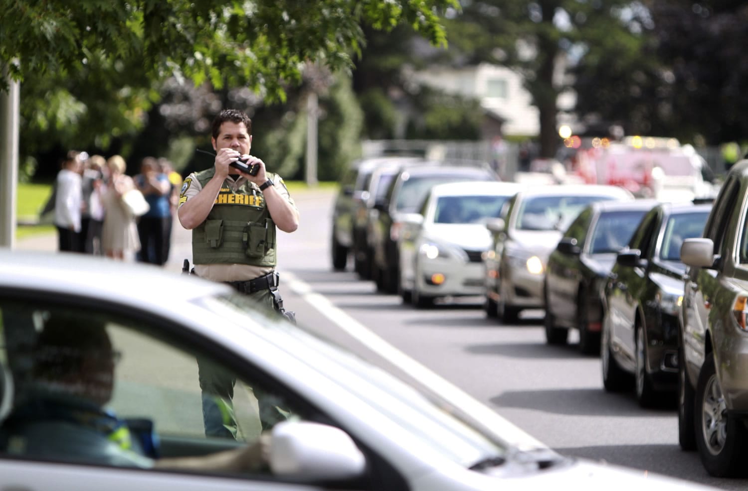 A sheriff's deputy speaks on his radio after a shooting at Reynolds High School on Tuesday, in Troutdale, Ore.