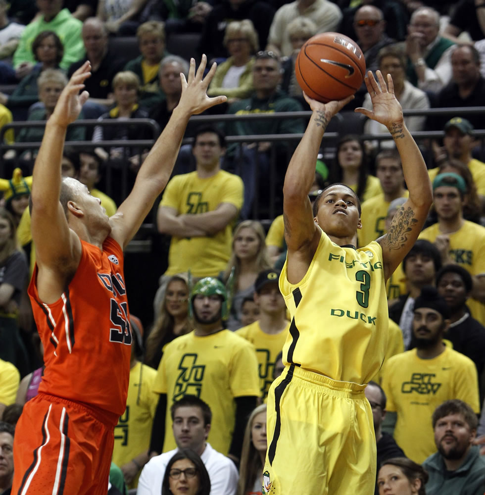 Oregon's Joseph Young, right, shoots a 3-point basket ahead of coverage by Oregon State's Roberto Nelson, left, during the first half at Eugene, Ore., on Sunday.