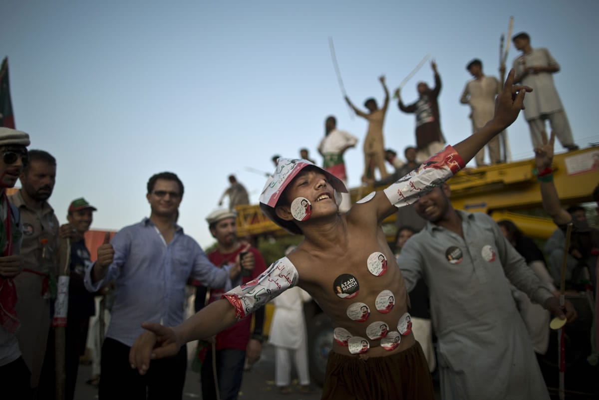 A young supporter of Pakistani cricketer-turned-politician Imran Khan, his body decorated with stickers showing Khan, dances with others during a protest in Islamabad, Pakistan, on Tuesday.