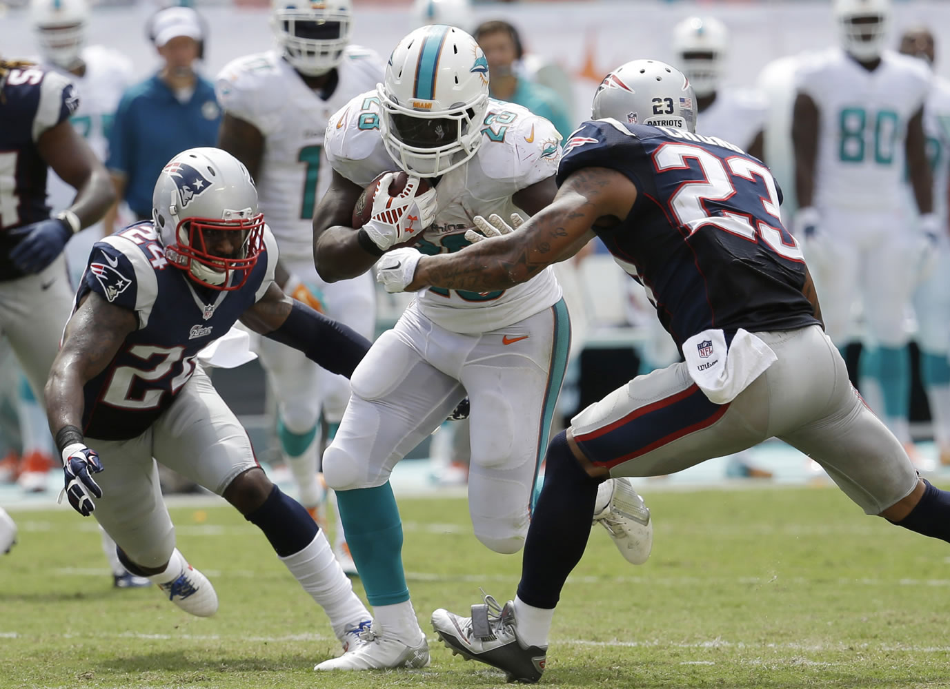 New England Patriots cornerback Darrelle Revis (24) and free safety Patrick Chung (23) attempt to tackle Miami Dolphins running back Knowshon Moreno (28) during the second half, Sunday Sept. 7, 2014. The Dolphins defeated the Patriots 33-20.