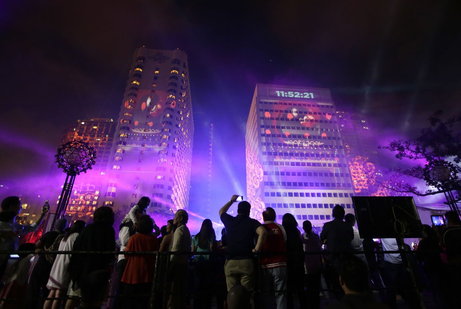 Revelers watch a laser show being projected on buildings as the countdown for the New Year begins in Manila, Philippines, on Wednesday.