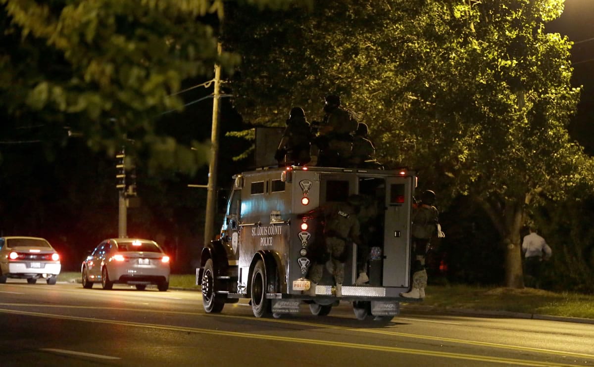 An armored personnel carrier speeds down the street Wednesday in Ferguson, Mo.