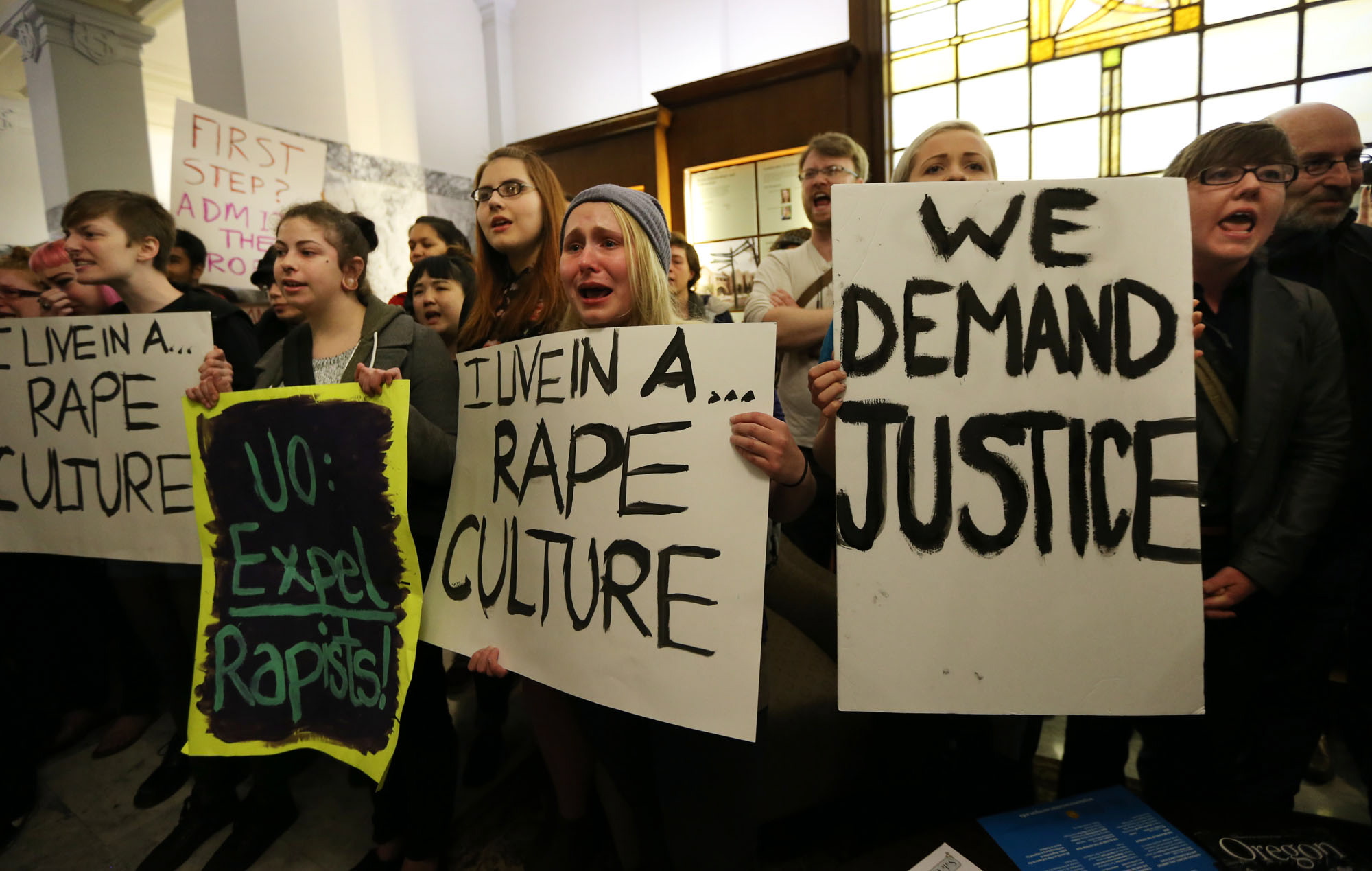 University of Oregon student Samantha Cohen, center, joins a hundred fellow protesters in the lobby of Johnson Hall on the UO campus in Eugene, Ore., Thursday to demand answers from school officials in the wake of allegations of sexual assault by three UO basketball players.