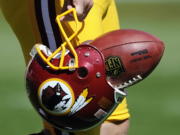 Washington Redskins punter Sav Rocca carries a football in his helmet Sept. 23, 2012before an NFL football game against the Cincinnati Bengals in Landover, Md. The U.S. Patent Office ruled Wednesday that the Washington Redskins nickname is &quot;disparaging of Native Americans&quot; and that the team's federal trademarks for the name must be canceled.