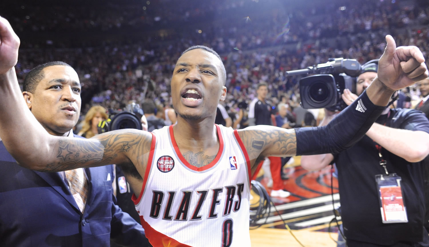Portland Trail Blazers' Damian Lillard, center, celebrates with fans, his winning shot against the Houston Rockets during the last .9 of a second of game six of an NBA basketball first-round playoff series game in Portland, Ore., Friday May 2, 2014. The Trail Blazers won the series in a 99-98 win.
