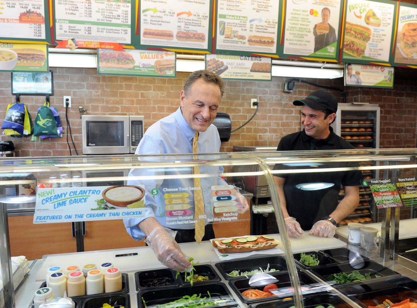 Fred DeLuca, left, co-founder and CEO of Subway, works behind the counter Tuesday at a Subway in New York.