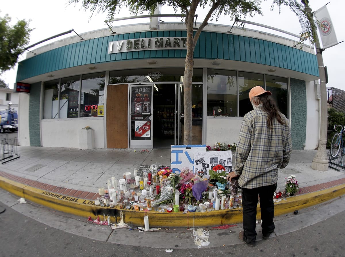 A passerby pays his respects at a makeshift memorial in front of the IV Deli Mart, Sunday, May 25, 2014, the scene of a drive-by shooting Friday in the Isla Vista area near Goleta, Calif. Calif. Sheriff's officials said Elliot Rodger, 22, went on a rampage near the University of California, Santa Barbara, stabbing three people to death at his apartment before shooting and killing three more in a crime spree through a nearby neighborhood.