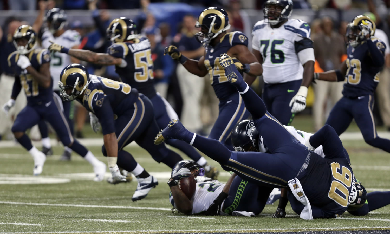 Seattle Seahawks running back Marshawn Lynch lands on his back as he is stopped on fourth down and St. Louis Rams players celebrate on the final play in overtime of an NFL football game Sunday, Sept. 13, 2015, in St. Louis. The Rams won 34-31.