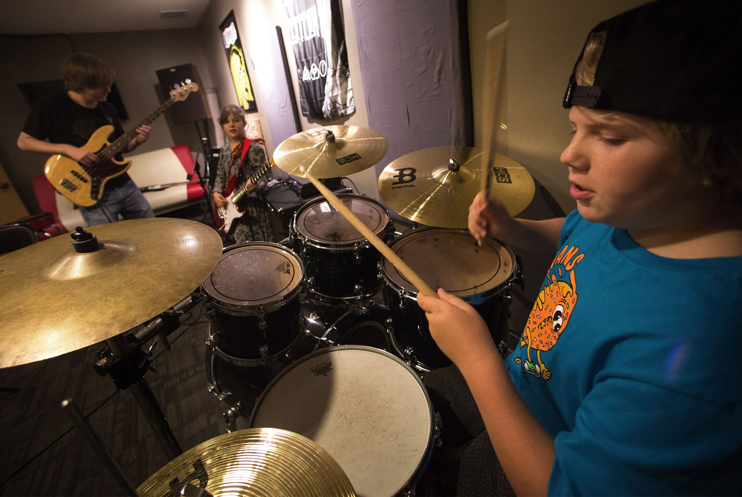 Under the instruction of Philip Gustason, left, general manager at the School of Rock in Seattle, Ro'ya Mottaghinejad, 8, back right, and Wade Beeler, right, jam together in a day camp at the school while Seattle teachers are on strike on Monday, Sept. 14, 2015. (Ellen M.