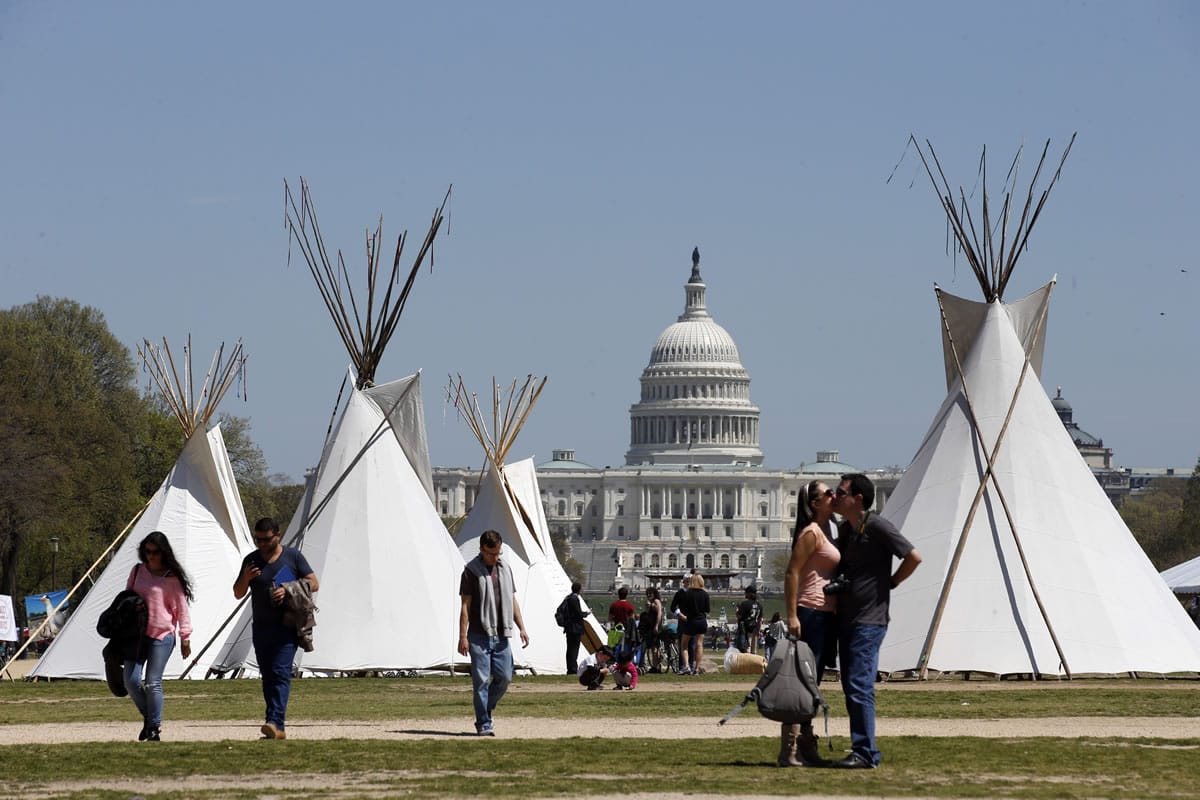 People walk near teepees set up on the National Mall in Washington, looking toward the Capitol.