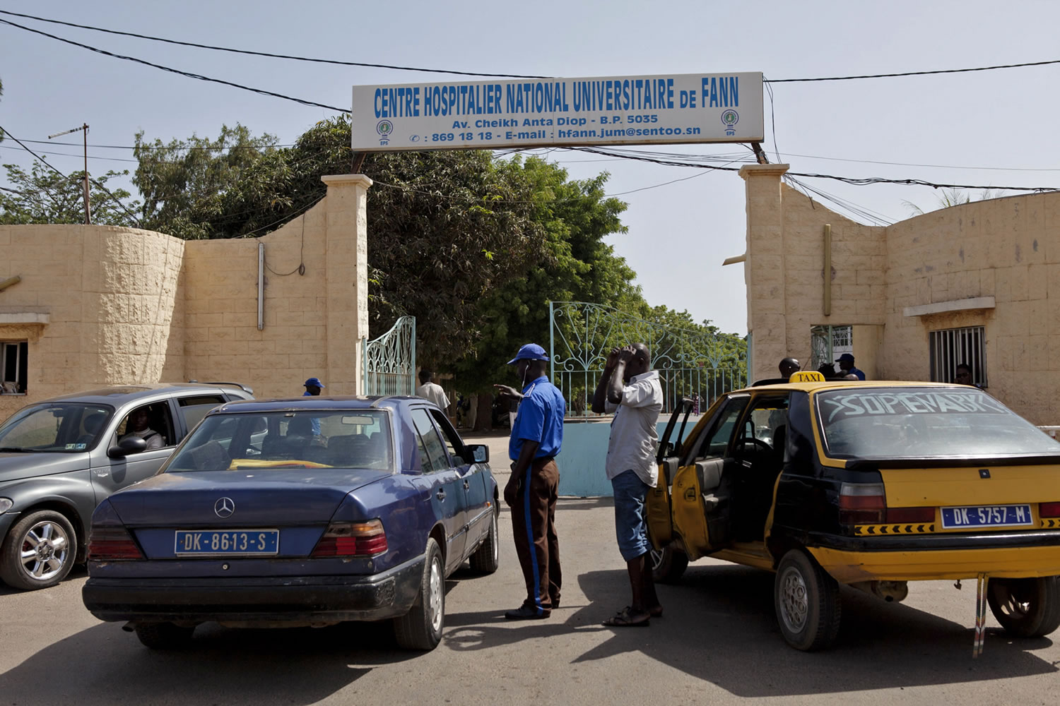 A security guard, center left, working at the University Hospital Fann, speaks to people inside a car Friday, as a man is  treated for symptoms of the Ebola virus inside the Hospital in Dakar, Senegal. The effort to contain Ebola in Senegal is ?a top priority emergency,?