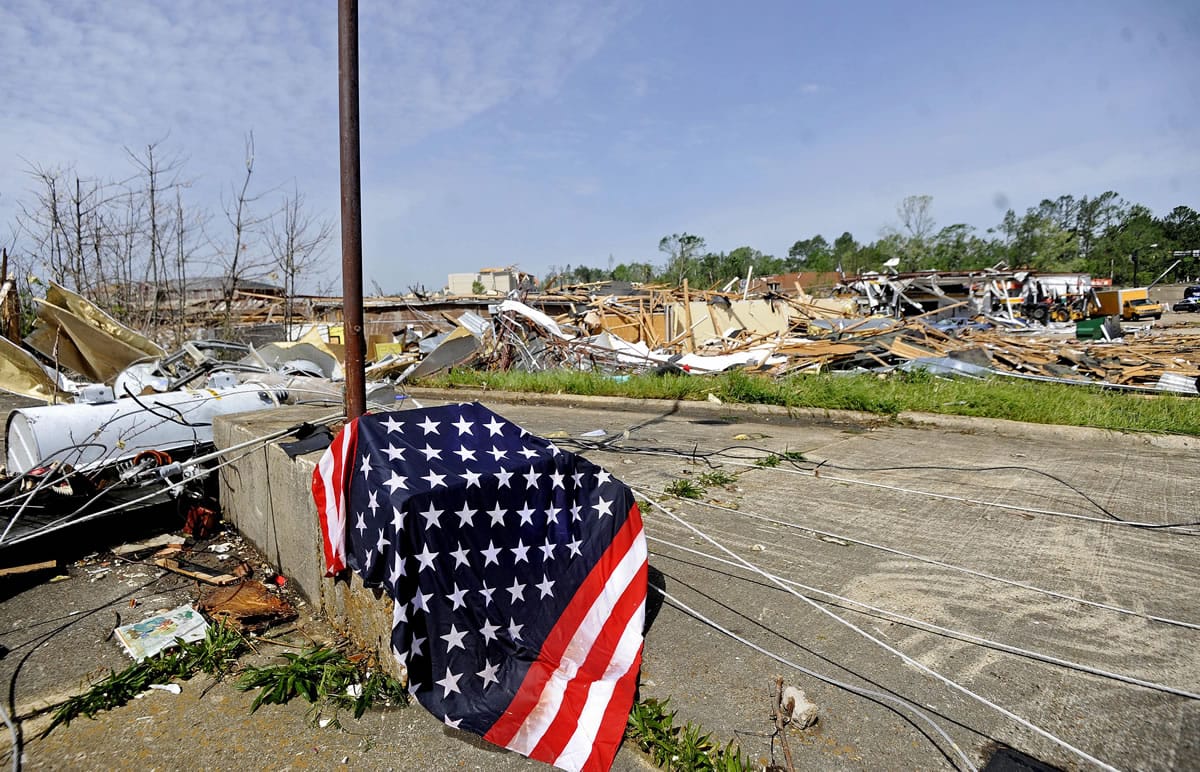 An American flag rests on a pillar as damaged buildings are seen in the background on North Gloster Street in Tupelo, Miss., on Tuesday.