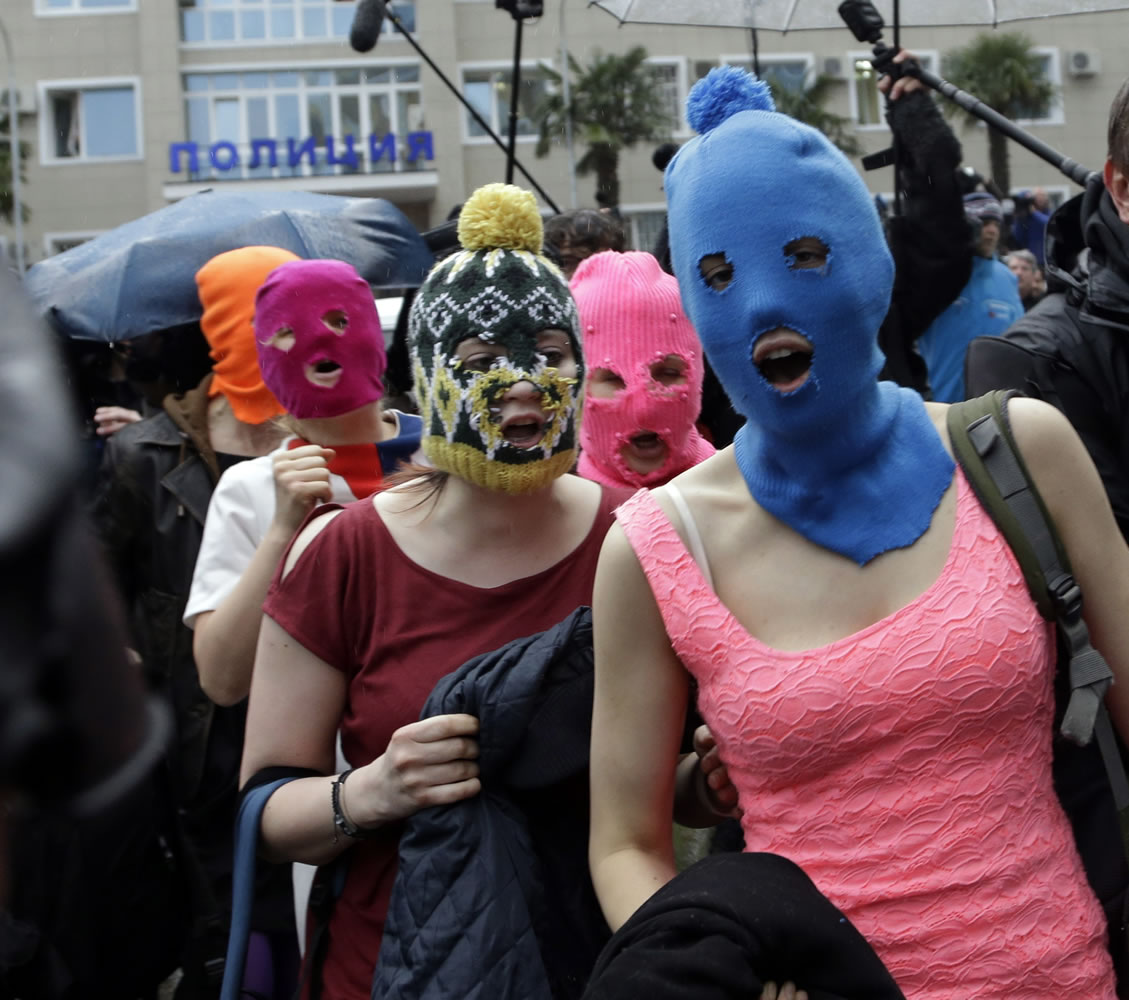 Five women wearing balaclavas, two of whom are members of the Russian punk group Pussy Riot, make their way through a crowd after they were released from a police station Tuesday 
 in Adler, Russia.